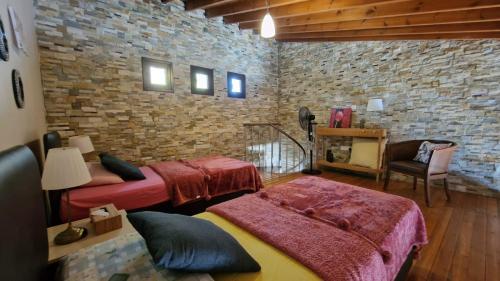 a bedroom with two beds and a brick wall at The Stone Villa in Pissouri