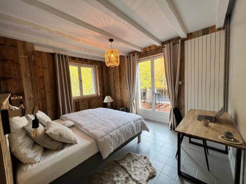 a bedroom with a bed and a table and a window at LES CIMES BLANCHES CLEDICIHOME Chalet 10 pers SPA & Grand terrain 4 MINUTES DES PISTES in La Bresse