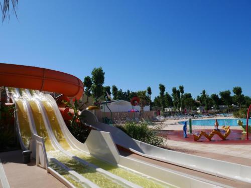 um escorrega aquático num resort com piscina em Mobil Home Palmiers 1 em Valras-Plage