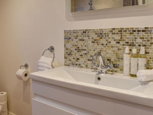 a bathroom with a sink with towels and a mirror at South Wing Coldharbour Park Farm in Rake