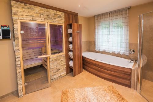 ein großes Bad mit einer Badewanne und einem Fenster in der Unterkunft Ferien beim Treiber in Bad Tatzmannsdorf