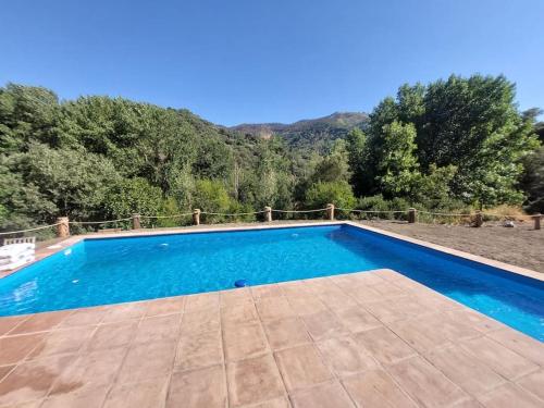 una piscina azul con una montaña en el fondo en Casa Barranco, en Júzcar