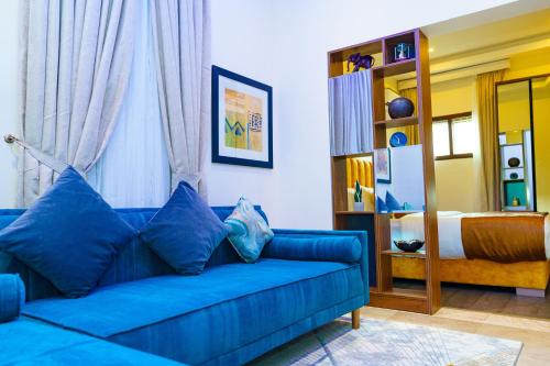 a blue couch in a living room with a bed at Qlets Privé in Abuja