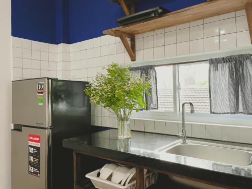 eine Küche mit einem Waschbecken und einer Vase aus Blumen in der Unterkunft Ivy house in Hue