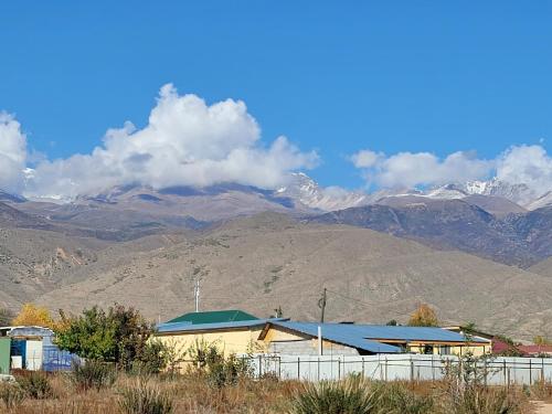 a building with snow covered mountains in the background at Ай-Ас in Cholpon-Ata