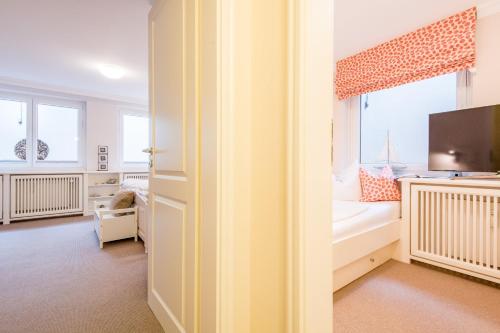 Un dormitorio con una cama y un televisor y una ventana. en Haus Sönshörn Whg 07, en Munkmarsch