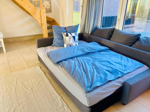 eine Couch mit blauer Decke drauf im Wohnzimmer in der Unterkunft Zwischen Wolfsburg, Tankumsee und Ilkerbruch - Apartment im Boldecker Land in Osloß
