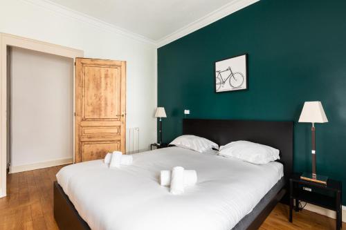 a bedroom with a large white bed with a green wall at DIFY Central - Bellecour in Lyon