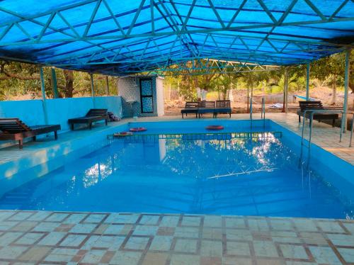 a large swimming pool with a blue roof at Gir Ganesh Farm & Resort in Sasan Gir