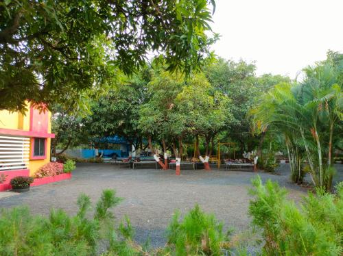 a park with tables and trees and a building at Gir Ganesh Farm & Resort in Sasan Gir