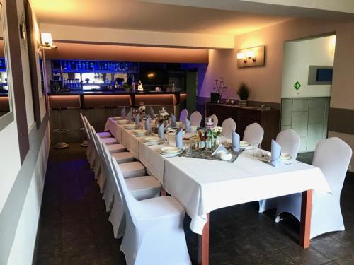 a long table in a restaurant with white tables and white chairs at Noclegi Hexe in Żegocina