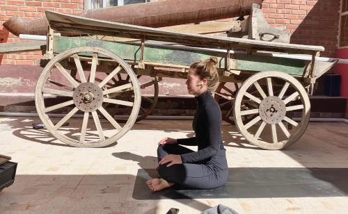 a woman sitting on the ground in front of a wagon at Tonito Hotel in Uyuni