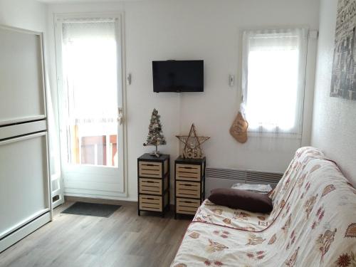 a living room with a couch and a tv and two windows at Studio Prapoutel 3 pers, balcon - FR-1-557-116 in Les Adrets