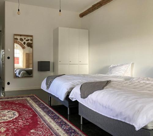 a bedroom with two beds and a mirror and a rug at Roslövs gård lantligt boende i Flyinge nära Lund och Malmö in Flyinge
