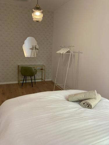 a bedroom with a white bed with a green chair at Minimal Hostel No.43 in Berlin