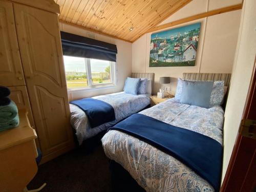 two beds in a small room with a window at Lake View Lodge in Millom