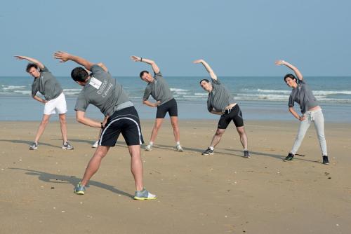 a group of people exercising on the beach at Thalazur Cabourg - Hôtel & Spa in Cabourg