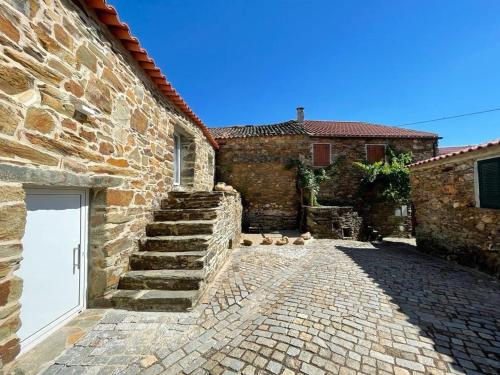 a stone building with a white door and a brick sidewalk at acalma - sesmo in Sarzedas