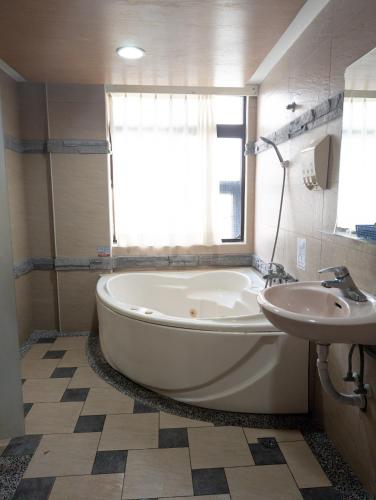 a bathroom with a large tub and a sink at Beethoven Express Hotel in Zhongli