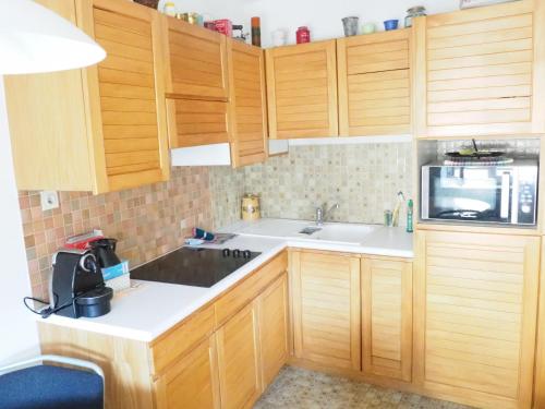 La cuisine est équipée de placards en bois, d'un évier et d'un four micro-ondes. dans l'établissement Le Tanneur, Appartement vintage hypercentre, à Strasbourg