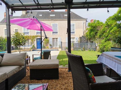 a patio with a couch and a pink umbrella at 5 Grande Rue in Le Lude