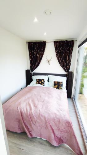 a pink bed in a bedroom with a window at Ranch 66 - Moderní Tiny House Black Swallow ve stylu Route 66 se saunou a bazénem in Tršice