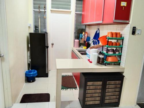 a small kitchen with red cabinets and a black refrigerator at MBI Homestay, Wakaf Che Yeh Kota Bharu in Wakaf Che Yeh