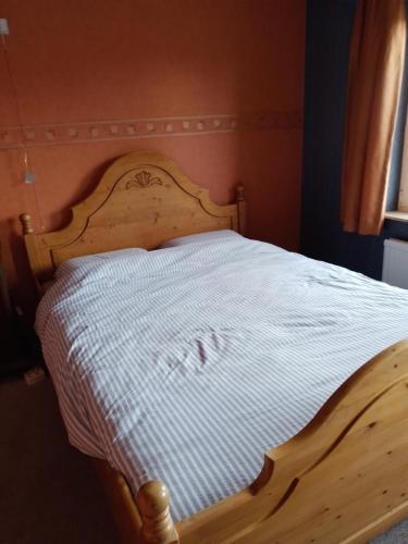 uma cama de madeira com uma colcha branca em Bed en Breakfast met patio en kippen em Thorn