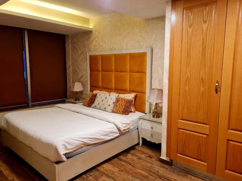 a bedroom with a large bed and a wooden door at Royal Residencia Centaurus in Islamabad