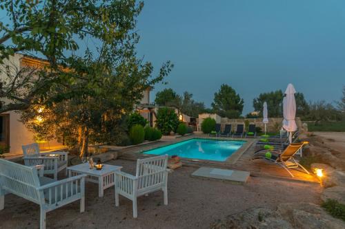 a swimming pool with chairs and a table and umbrella at Son Indiot in Algaida