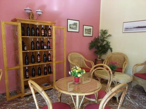 Hotel Pensione Cundari في تاورمينا: غرفة مع طاولة ورف من زجاجات النبيذ