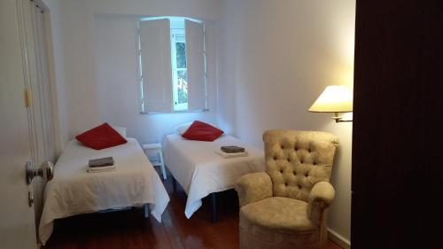 リスボンにあるPilar - Alfama River Viewのベッド2台、椅子、窓が備わる客室です。