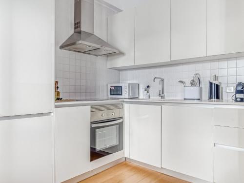 a white kitchen with white cabinets and a microwave at limehome Madrid San Lorenzo in Madrid