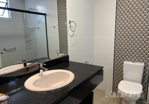 a bathroom with a sink and a toilet and a mirror at Complexo Eco Cataratas Resort by SJ in Foz do Iguaçu