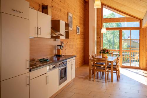 eine Küche mit weißen Schränken und einem Tisch mit Stühlen in der Unterkunft Ferienwohnungen Erlebnisnaturhof in Aschau im Chiemgau