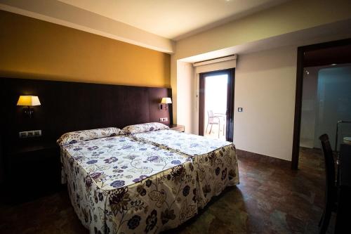 a bedroom with a bed with a floral bedspread at Hostal Restaurante La Bartola in Santa Cruz