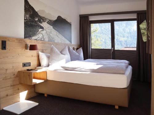 een slaapkamer met een groot bed en een raam bij Lechappart in Höfen