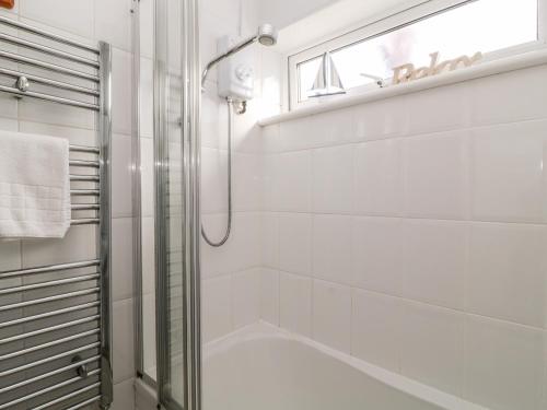 uma casa de banho branca com um chuveiro e uma porta de vidro em 32 Manorcombe em Callington