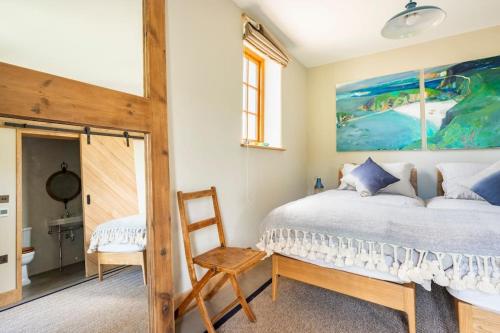 a bedroom with a bed and a chair at Fledgling Barn: stunning new coastal holiday home in Kingsbridge