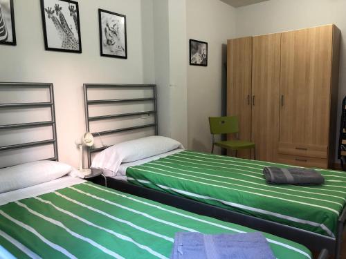 a bedroom with two beds and a cabinet at Apartamentos Ribera Navarra - Bardenas in Castejón