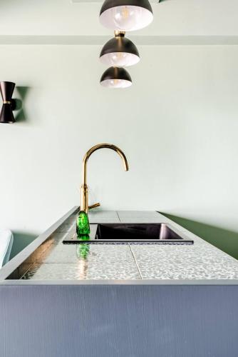 a kitchen sink with a green bottle on it at Luxueuze suite met frontaal zeezicht in Knokke-Heist