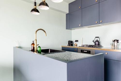 a kitchen with blue cabinets and a sink at Luxueuze suite met frontaal zeezicht in Knokke-Heist