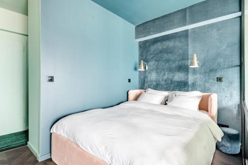 a bedroom with a large white bed with blue walls at Luxueuze suite met frontaal zeezicht in Knokke-Heist