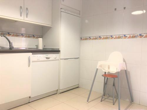 a kitchen with white cabinets and a stool in it at Apartamentos Ribera Navarra - Bardenas in Castejón