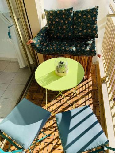 Cette chambre comprend une table verte et une chaise. dans l'établissement Le Bleuette - Festivals 10min - face plages !, à Cannes