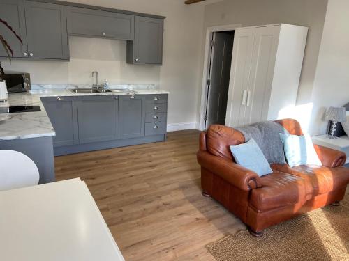 a living room with a leather chair and a kitchen at Potcote farm stables accommodation spots stable in Towcester