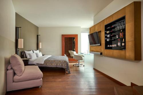 a bedroom with a bed and a couch and a chair at DO&CO Hotel Vienna in Vienna