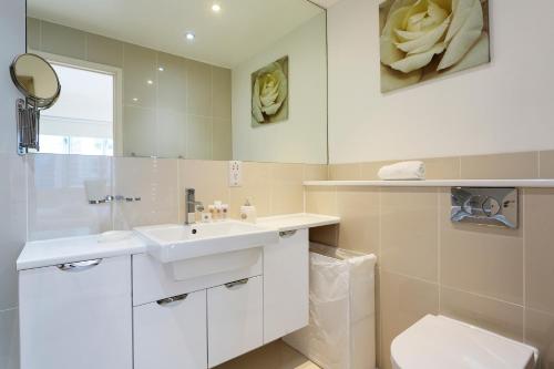 ein Badezimmer mit einem Waschbecken, einem WC und einem Spiegel in der Unterkunft Veeve - Village Virtuosity in London