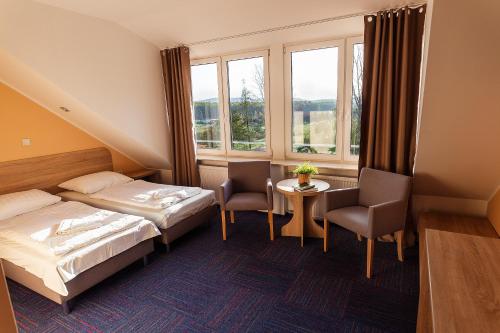 a hotel room with two beds and a table and two chairs at Ośrodek Chrobry in Pokrzywna