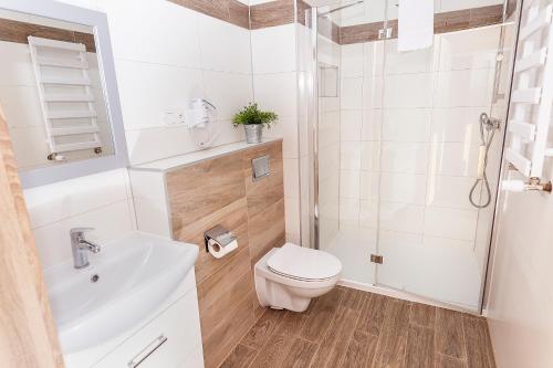 a white bathroom with a toilet and a shower at Ośrodek Chrobry in Pokrzywna